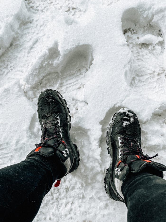 Close-up of hiking boots walking in fresh snow, showcasing winter adventure footwear.